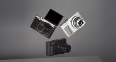 Tri kompaktné fotoaparáty Panasonic Lumix v čiernej, bielej a striebornej farbe sú zobrazené na sivom pozadí, čo zvýrazňuje rôzne možnosti dizajnu.