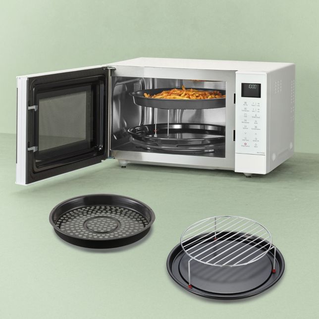 Kuchenka mikrofalowa Panasonic Slim Line Combi z otwartymi drzwiczkami i potrawą w środku. Z przodu widoczne akcesoria: kosz Air Fry, ruszt grillowy i tacka emaliowana.