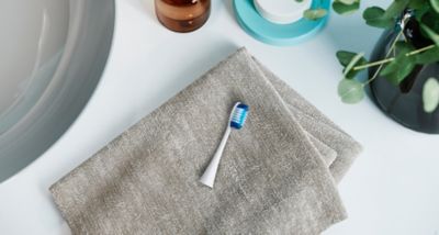 Capul de periere Extra-fine Brush WEW0801W așezat pe un prosop împăturit în zona lavoarului