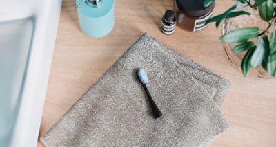 Capul de periere Stain-off Brush WEW0882K așezat pe un prosop împăturit în zona lavoarului
