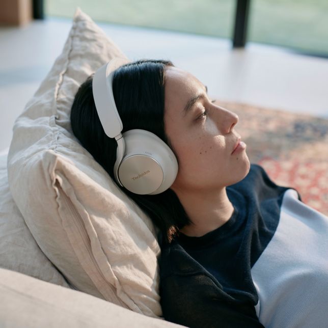 Woman relaxing with Technics EAH-A1000 headphones, demonstrating immersive spatial audio with head tracking.